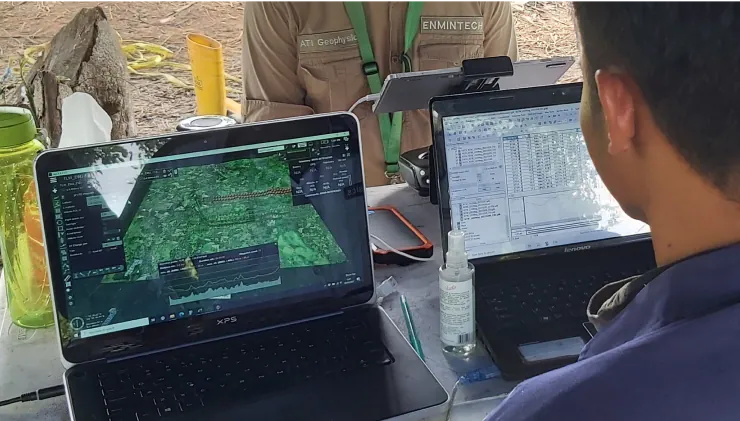 Enmintech team conducting geophysical survey on laptops in the field